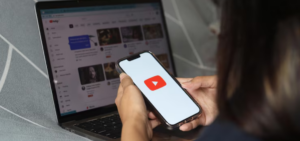 pessoa segurando um celular com a tela do dispositivo exibindo o logotipo do YouTube