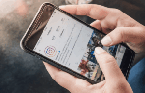 mãos mexendo em celular com instagram em tela